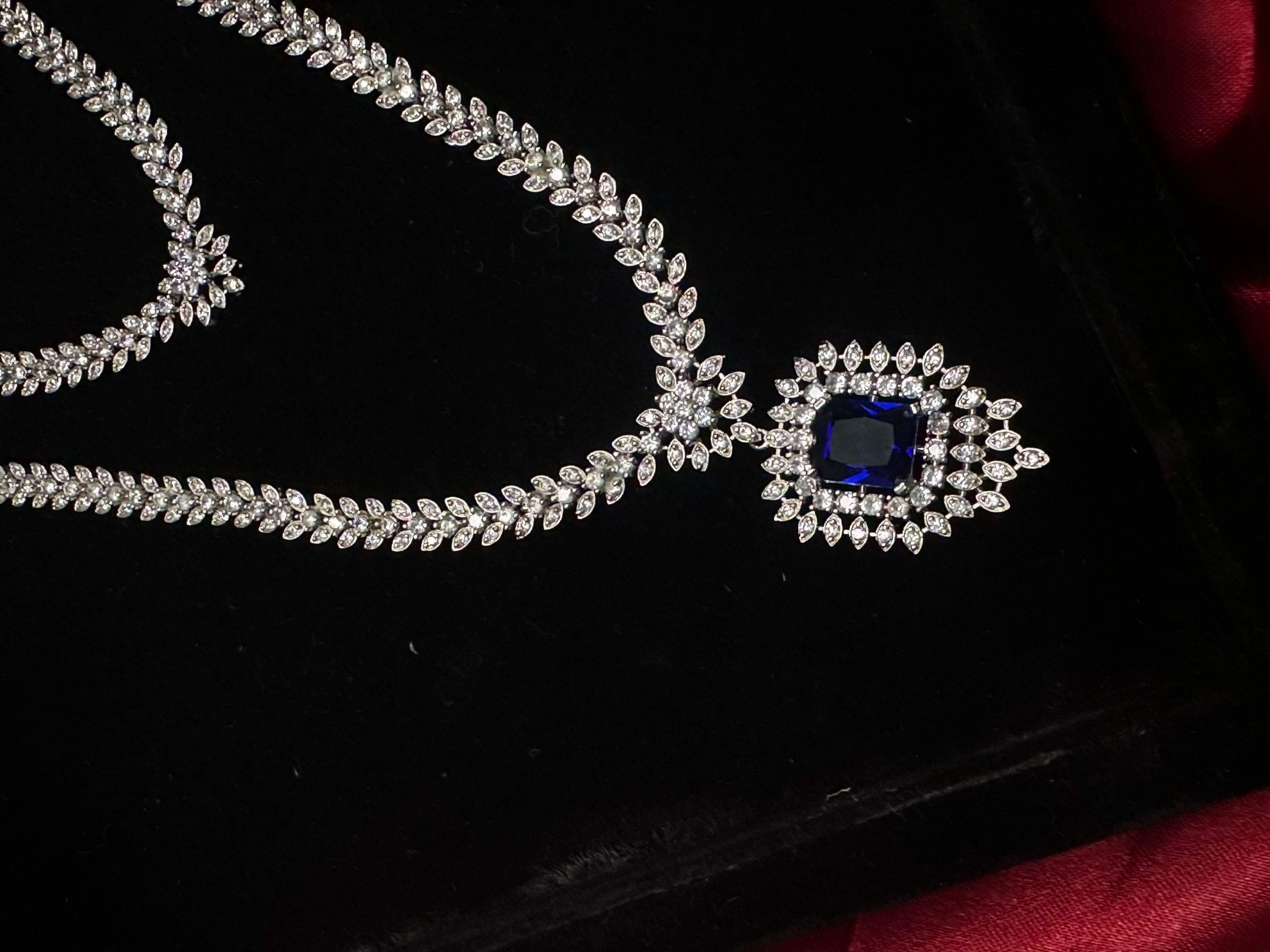 Silver necklace with a blue gemstone pendant on a black background