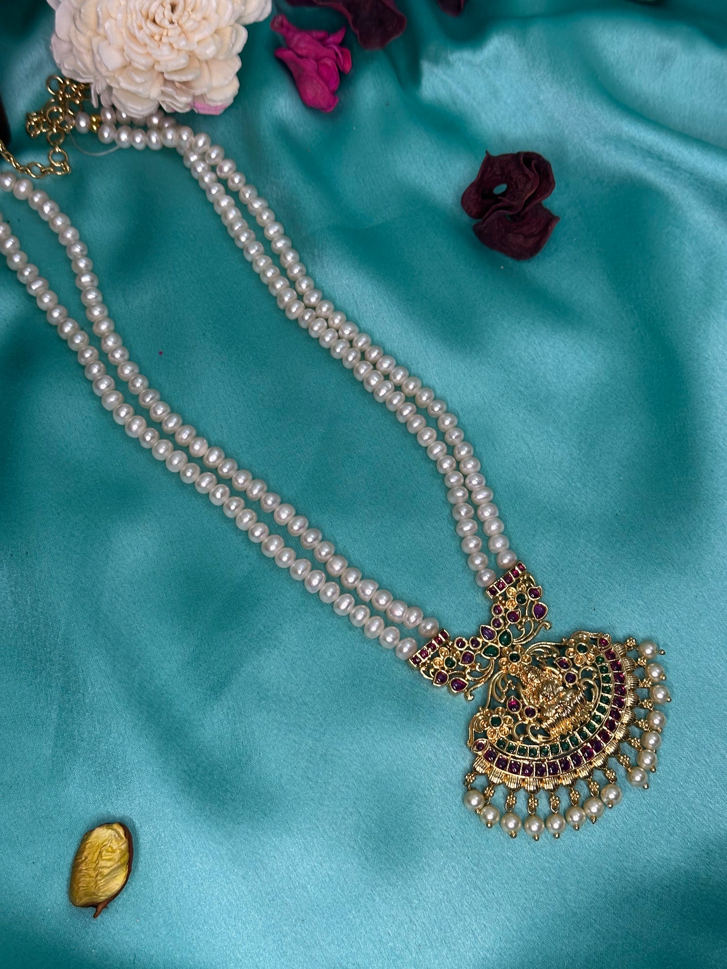 Pearl necklace with a gold pendant on a blue satin background