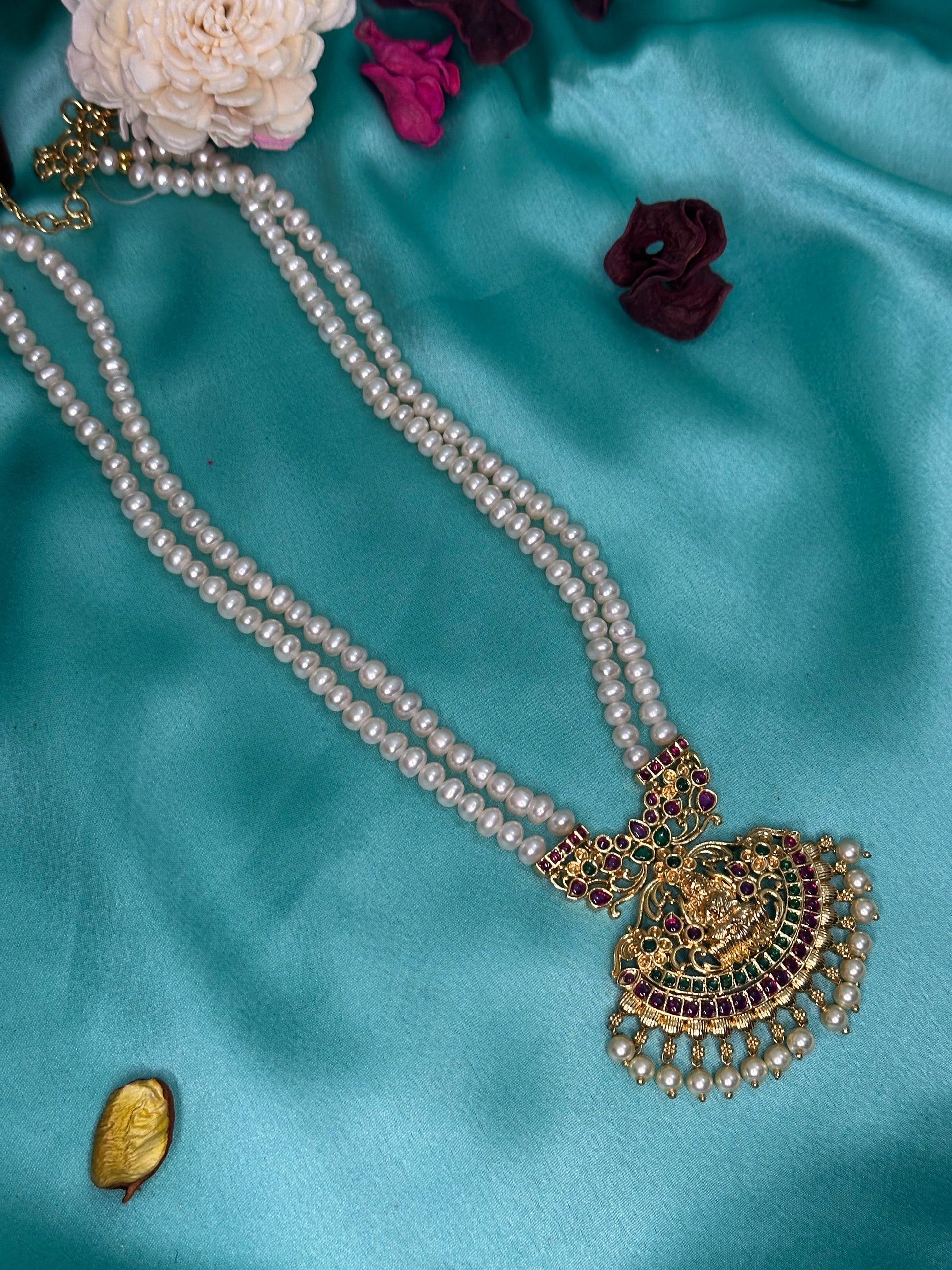 Pearl necklace with a gold pendant on a blue satin background